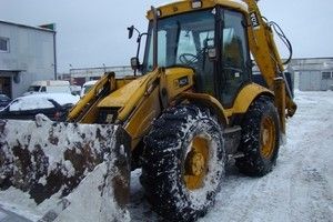 Трактор-погрузчик JCB для погрузки снега в самосвал или контейнер